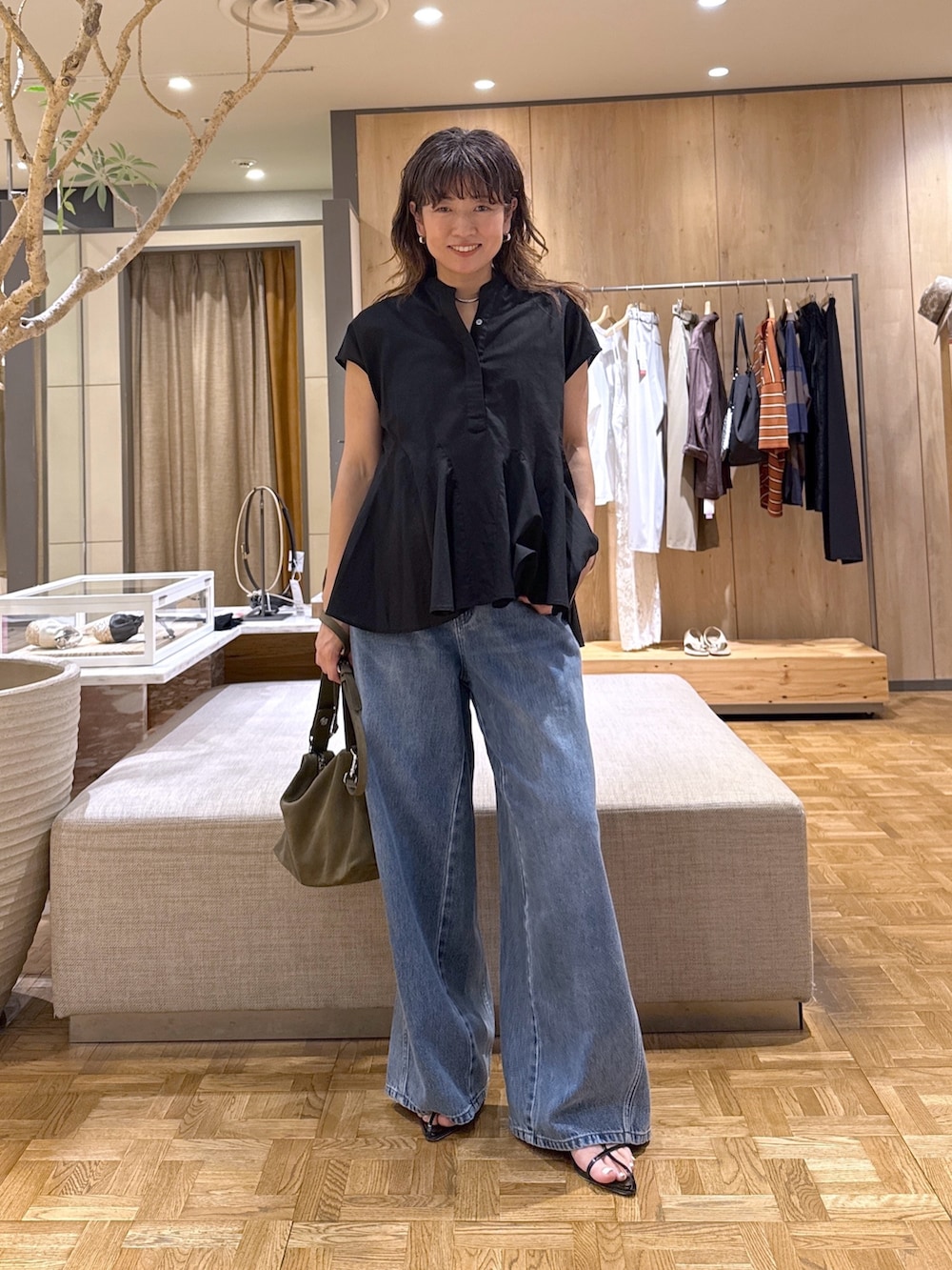 ブルー系のデニムパンツ、ブラック系のサンダル、グリーン系のトートバッグを着用したレディースの夏コーディネートの3枚目の写真