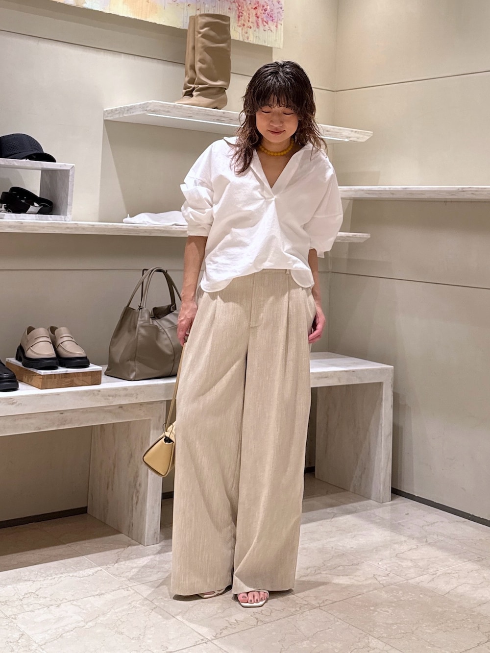 ベージュ系のスラックス、ベージュ系のハンドバッグ、ホワイト系のシャツ/ブラウスを着用したレディースの春コーディネートの3枚目の写真