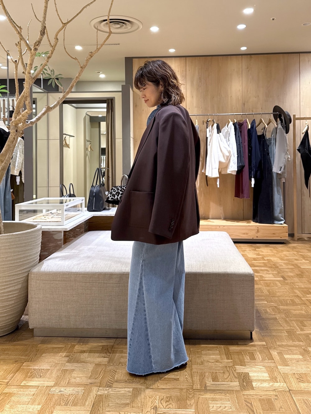 ブルー系のシャツ/ブラウス、ブルー系のデニムパンツ、ブラック系のトートバッグを着用したレディースの秋コーディネートの2枚目の写真
