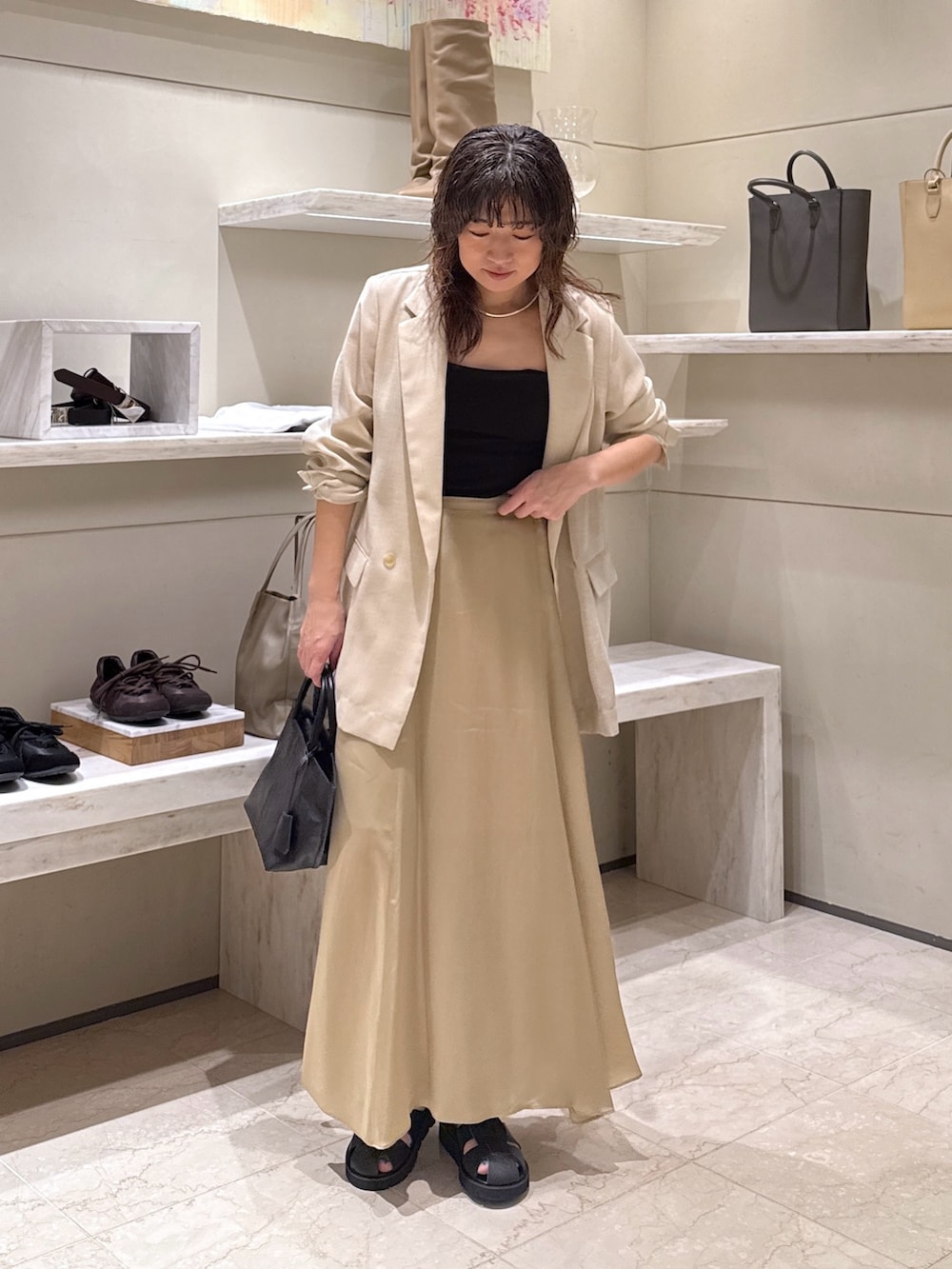 ベージュ系のスカート、ブラック系のトートバッグ、ブラック系のサンダルを着用したレディースの春コーディネートの2枚目の写真