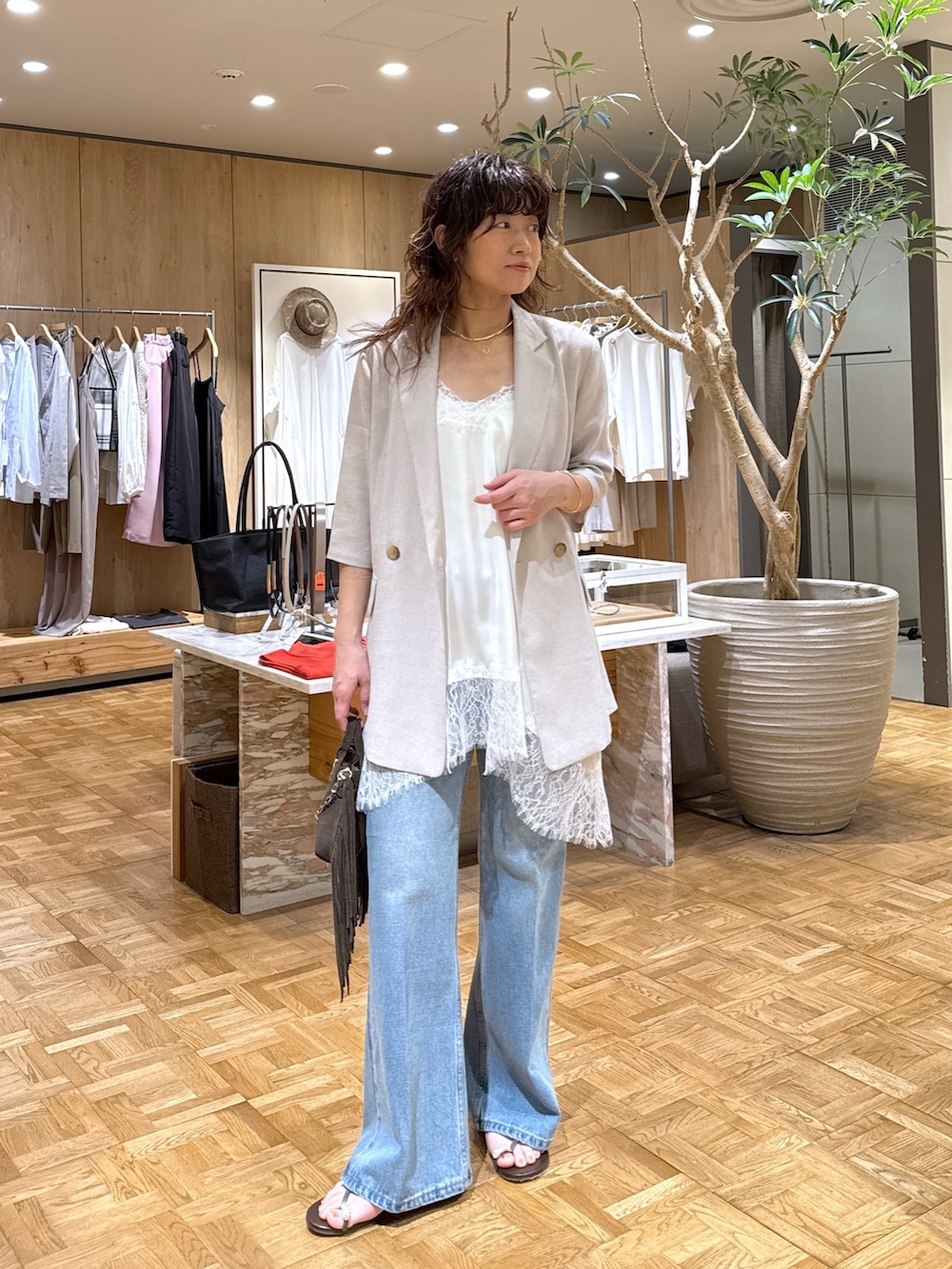ベージュ系のテーラードジャケット、ブルー系のデニムパンツ、ブラウン系のハンドバッグを着用したレディースの春コーディネートの2枚目の写真