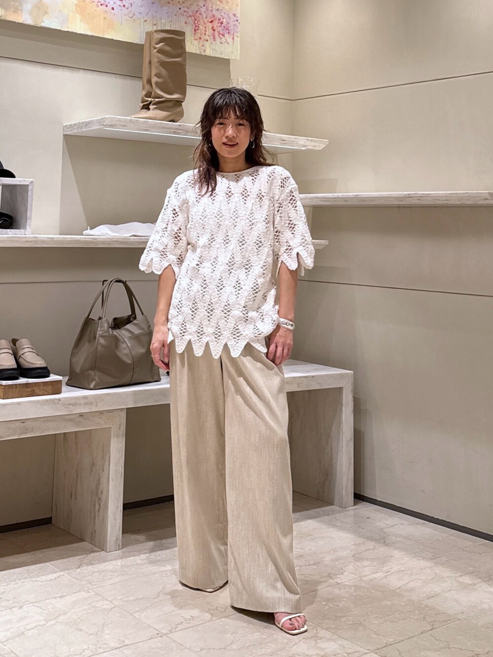 ホワイト系のシャツ/ブラウス、ベージュ系のスラックス、シルバー系のバングル/リストバンドを着用したレディースの春コーディネートの2枚目の写真