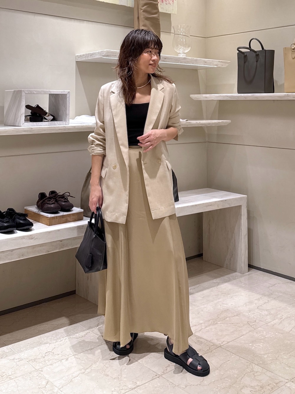 ベージュ系のスカート、ブラック系のトートバッグ、ブラック系のサンダルを着用したレディースの春コーディネートの4枚目の写真