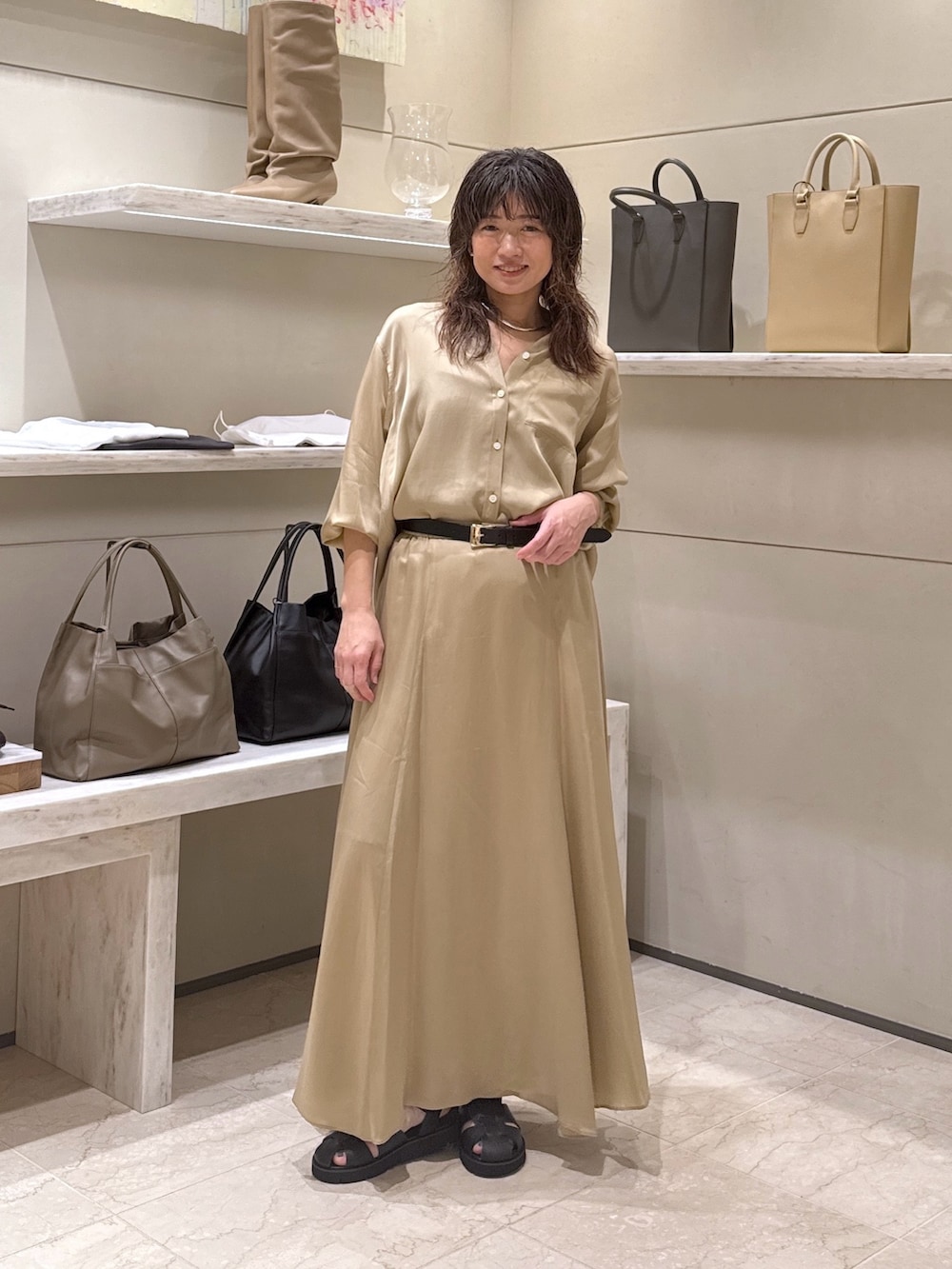 ベージュ系のスカート、ベージュ系のシャツ/ブラウス、ブラック系のサンダルを着用したレディースの春コーディネートの2枚目の写真