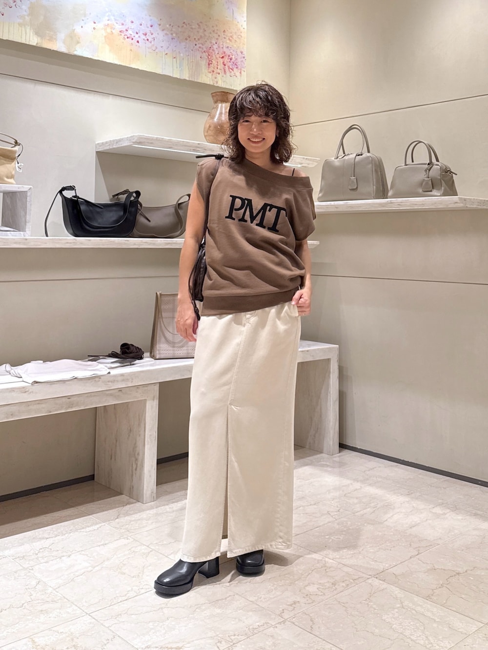 ホワイト系のスカート、ブラウン系のショルダーバッグ、ブラック系のブーツを着用したレディースの夏コーディネートの4枚目の写真