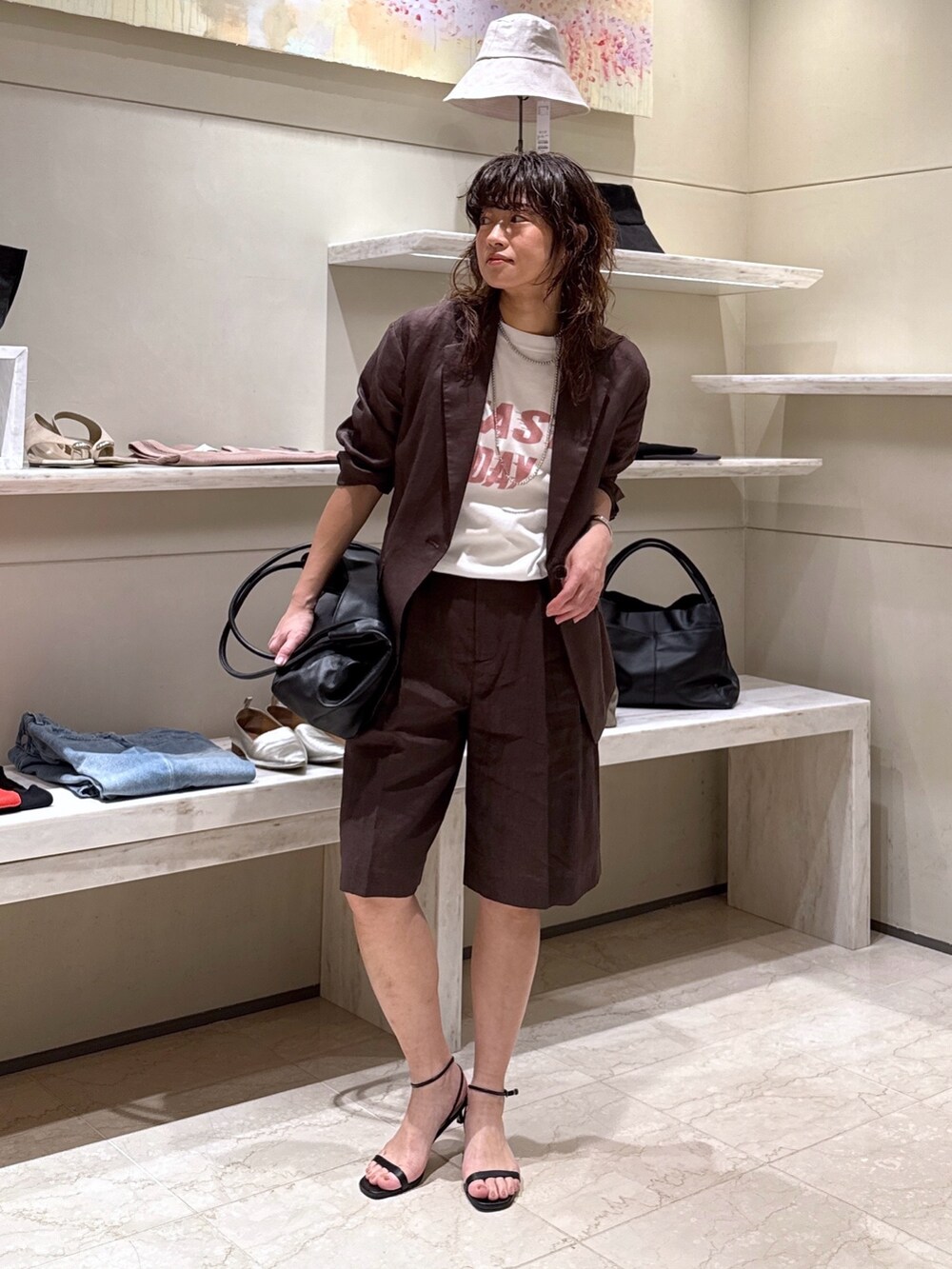 ブラウン系のその他パンツ、ブラック系のトートバッグ、ホワイト系のTシャツ/カットソーを着用したレディースの春コーディネートの2枚目の写真