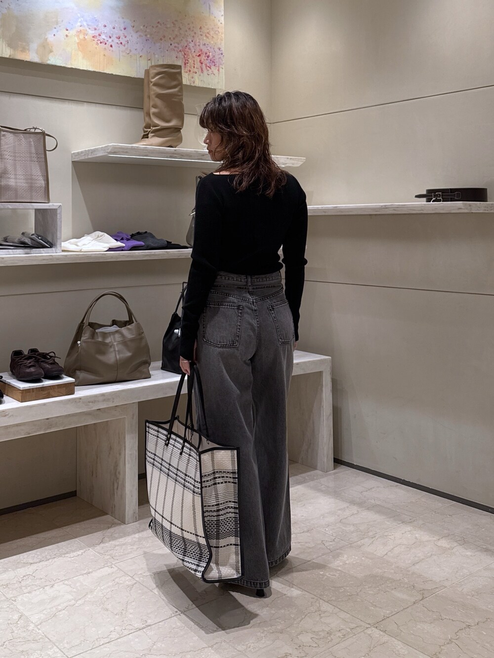 グレー系のデニムパンツ、ブラック系のサンダル、ブラック系のトートバッグを着用したレディースの冬コーディネートの3枚目の写真