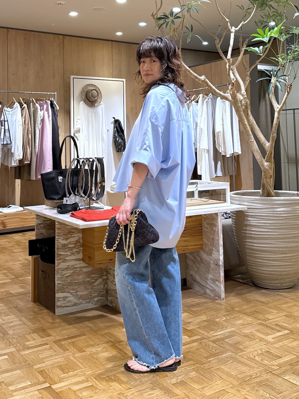 ブルー系のシャツ/ブラウス、ブルー系のデニムパンツ、ブラック系のショルダーバッグを着用したレディースの春コーディネートの2枚目の写真