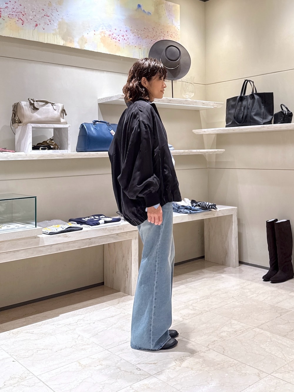 ブルー系のデニムパンツ、ブラック系のブーツ、ブラック系のトートバッグを着用したレディースの秋コーディネートの2枚目の写真