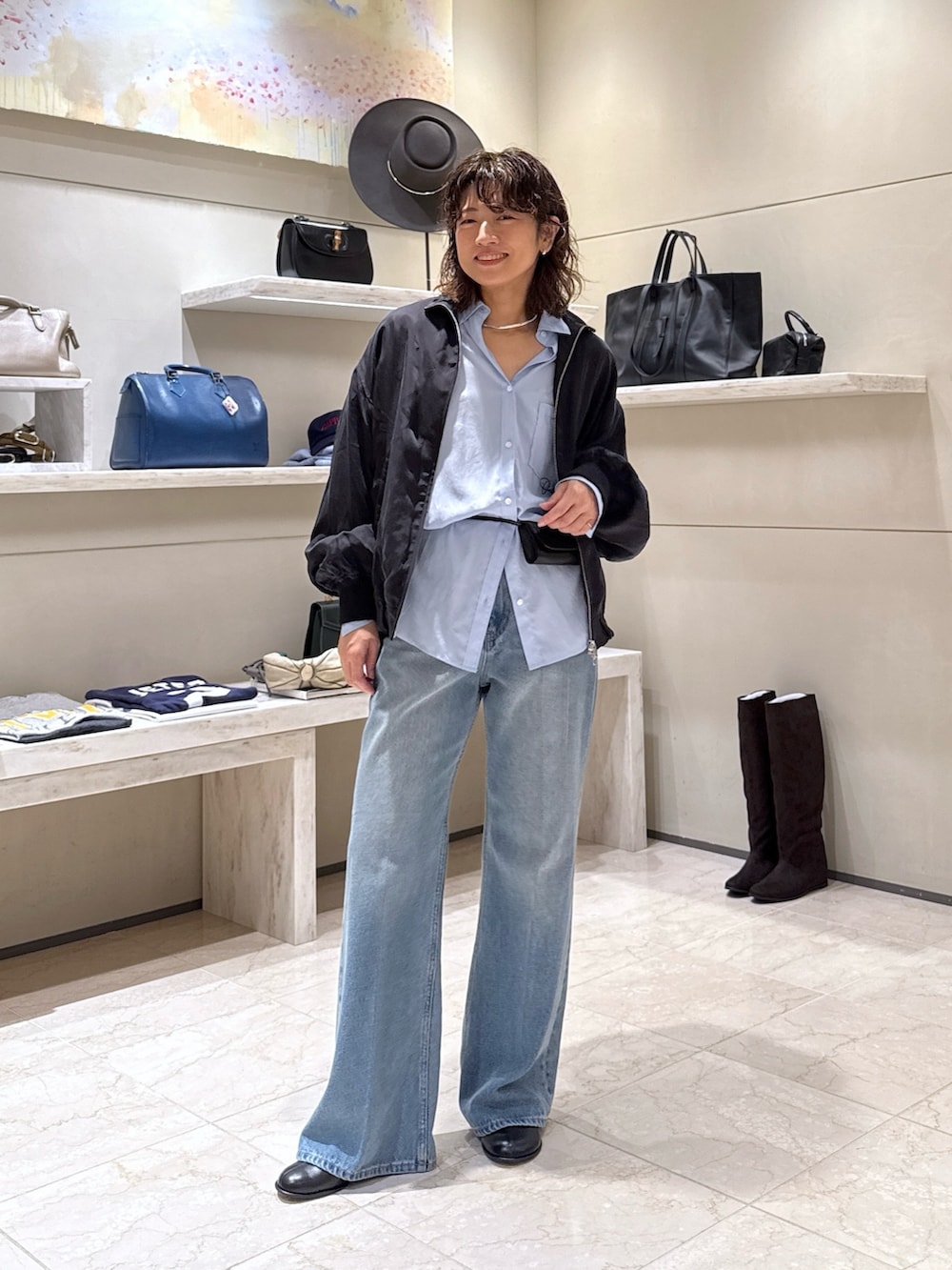 ブルー系のデニムパンツ、ブラック系のブーツ、ブラック系のトートバッグを着用したレディースの秋コーディネートの4枚目の写真