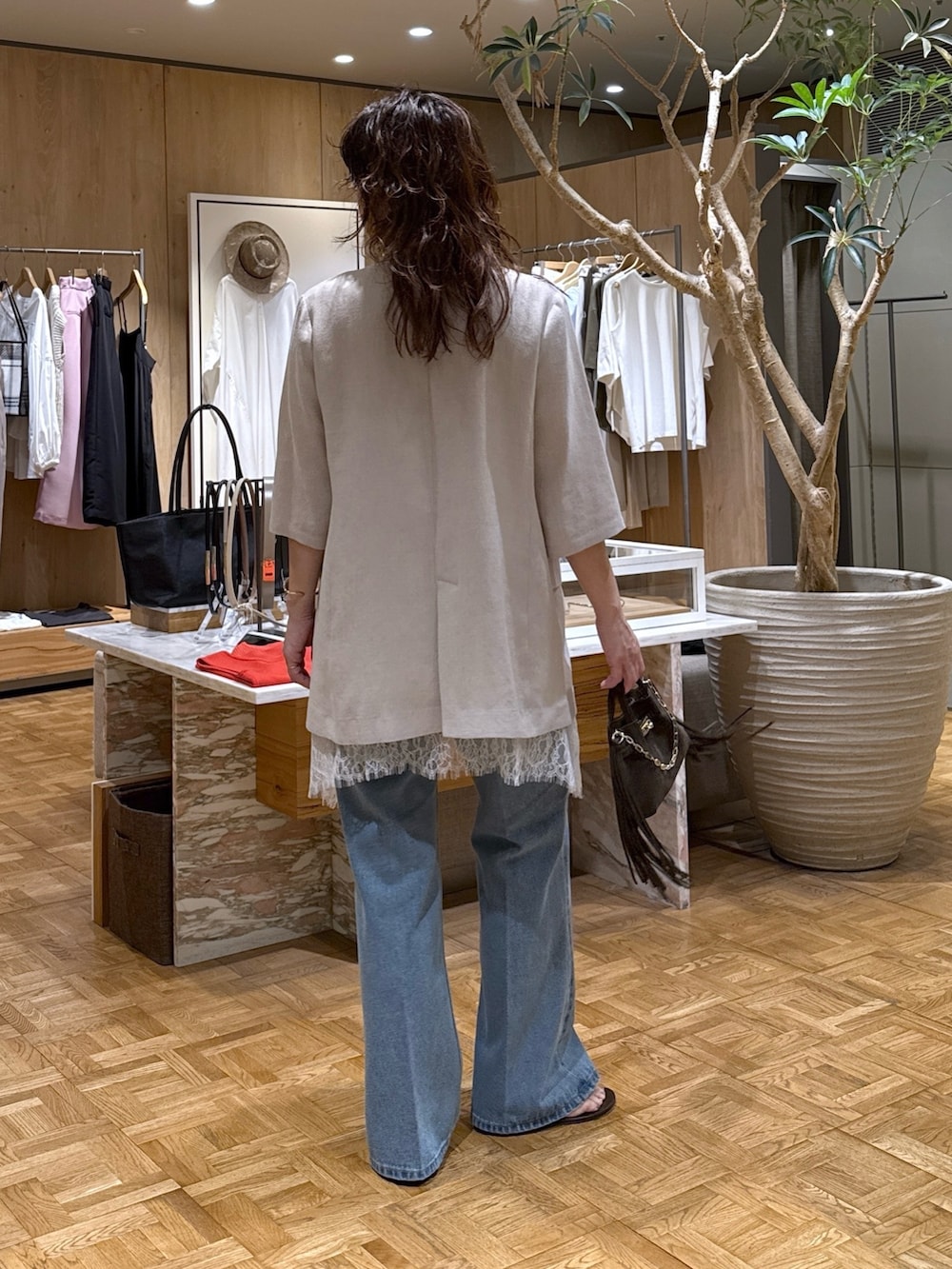 ベージュ系のテーラードジャケット、ブルー系のデニムパンツ、ブラウン系のハンドバッグを着用したレディースの春コーディネートの3枚目の写真
