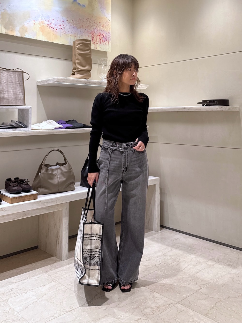 グレー系のデニムパンツ、ブラック系のサンダル、ブラック系のトートバッグを着用したレディースの冬コーディネートの2枚目の写真