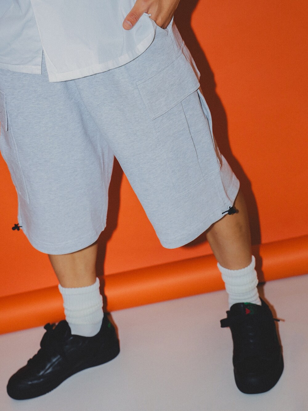 ホワイト系のシャツ/ブラウス、シルバー系のカーゴパンツ、ブラック系のスニーカーを着用したメンズの夏コーディネートの3枚目の写真