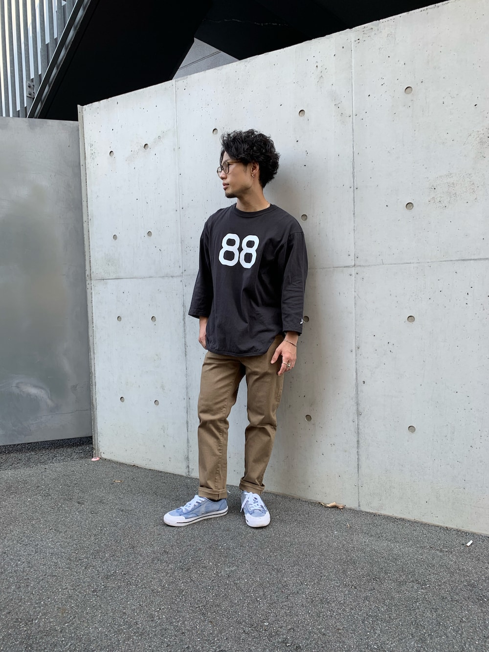 ブラック系のTシャツ/カットソー、ブラウン系のチノパンツ、ブルー系のスニーカーを着用したメンズの夏コーディネートの2枚目の写真