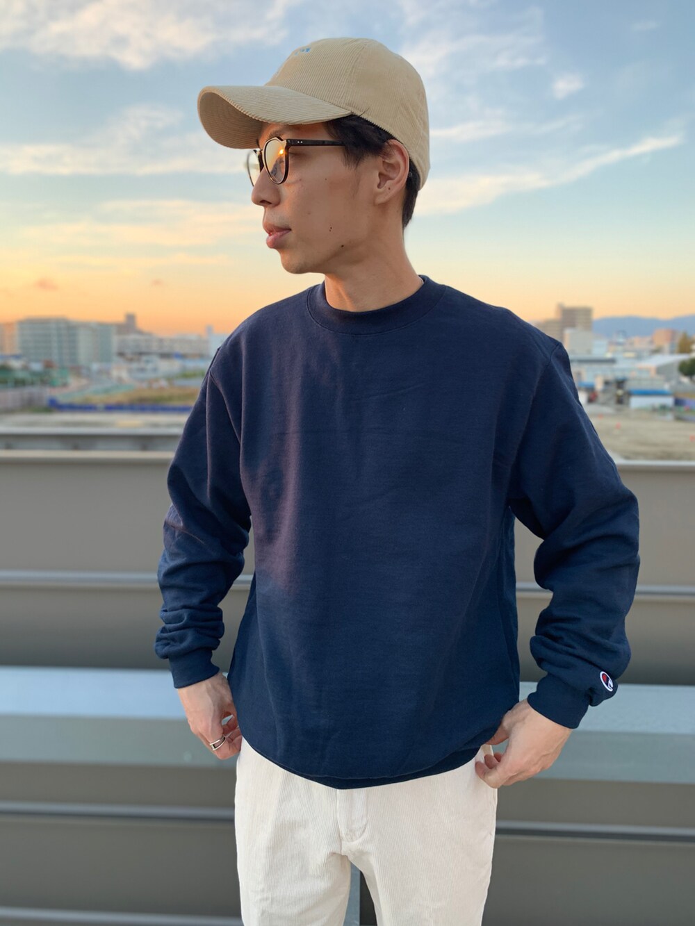 ブルー系のスウェット、ホワイト系のパンツ、ブラック系のスニーカーを着用したメンズの秋コーディネートの2枚目の写真