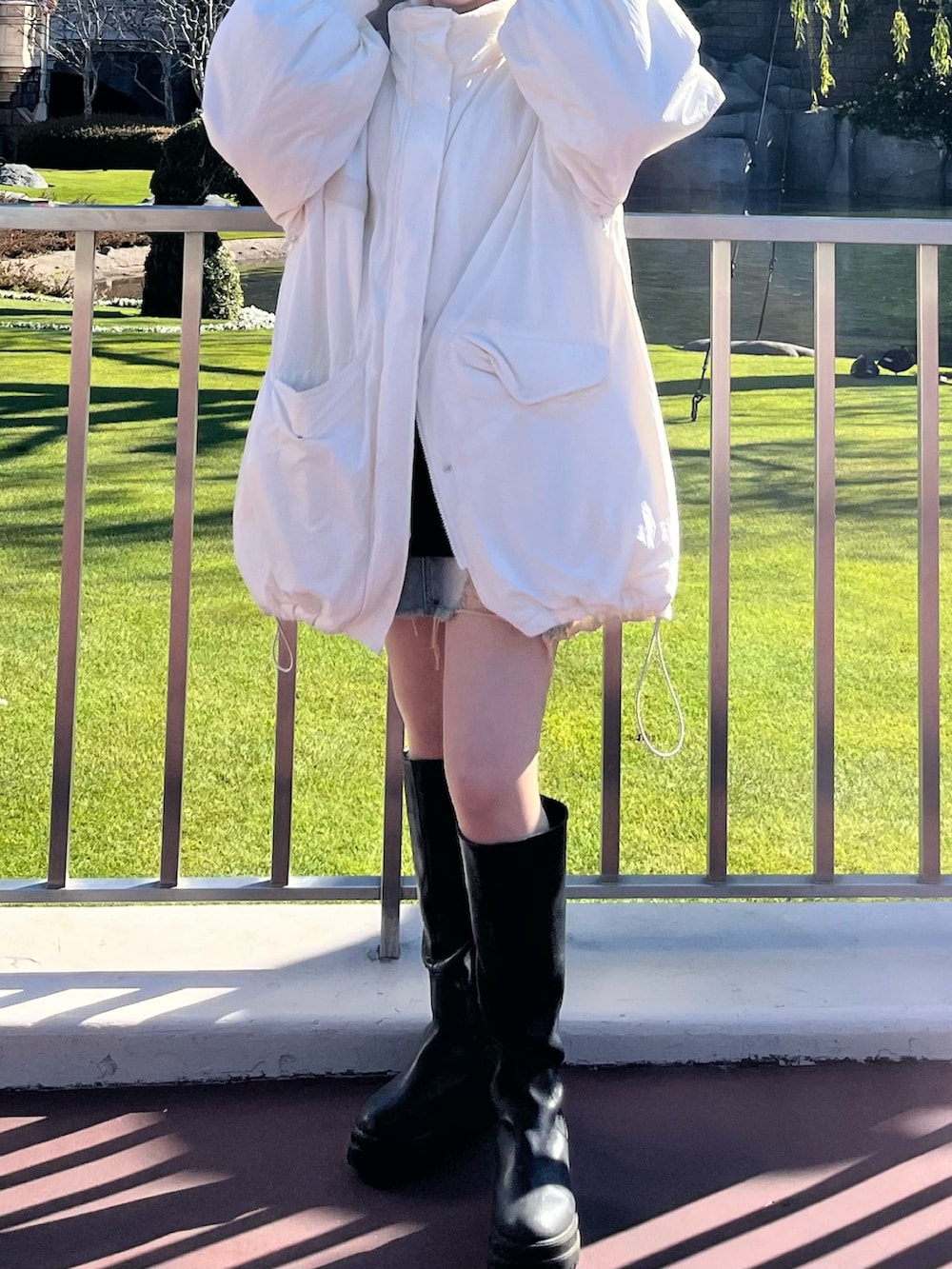 ブラック系のブーツ、ホワイト系のジャケット/アウター、ブラック系のニット/セーターを着用したレディースの春コーディネートの3枚目の写真