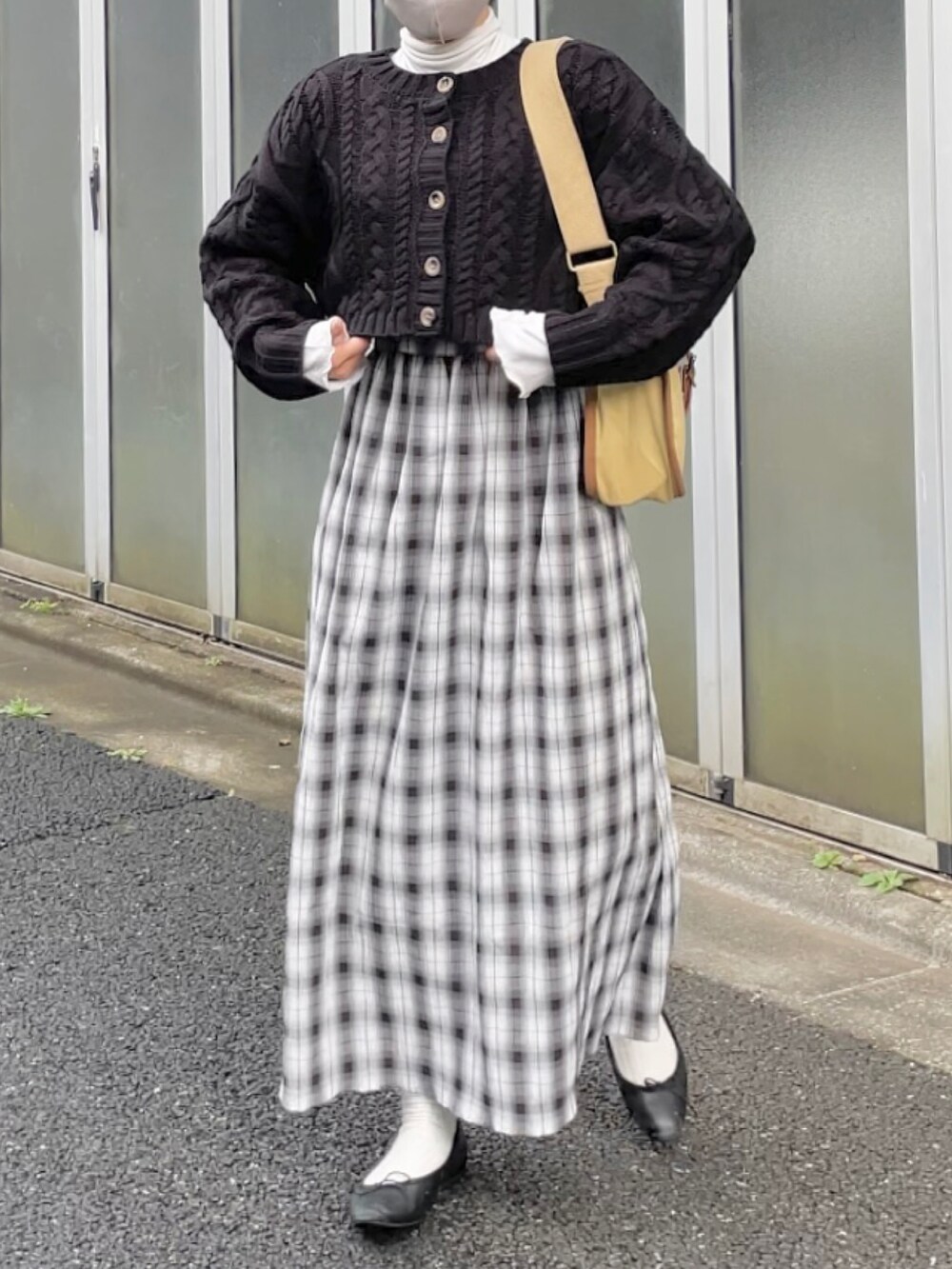 ブラック系のニット/セーター、ホワイト系のワンピース、ベージュ系のショルダーバッグを着用したレディースの秋コーディネートの3枚目の写真