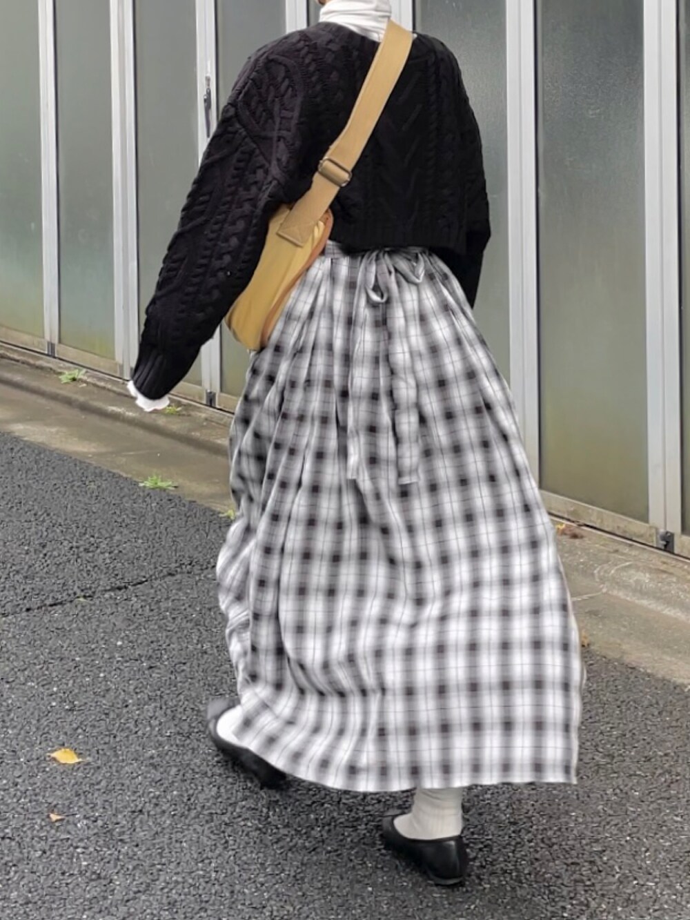 ブラック系のニット/セーター、ホワイト系のワンピース、ベージュ系のショルダーバッグを着用したレディースの秋コーディネートの4枚目の写真