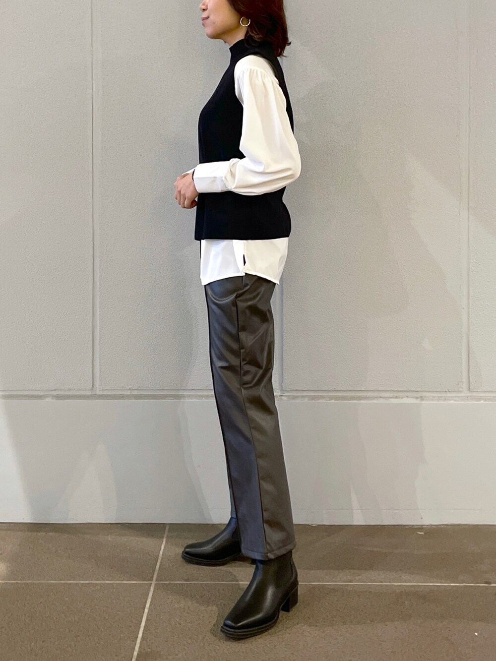 ブラック系のベスト、グレー系のその他パンツ、ブラック系のブーツを着用したレディースの秋コーディネートの2枚目の写真