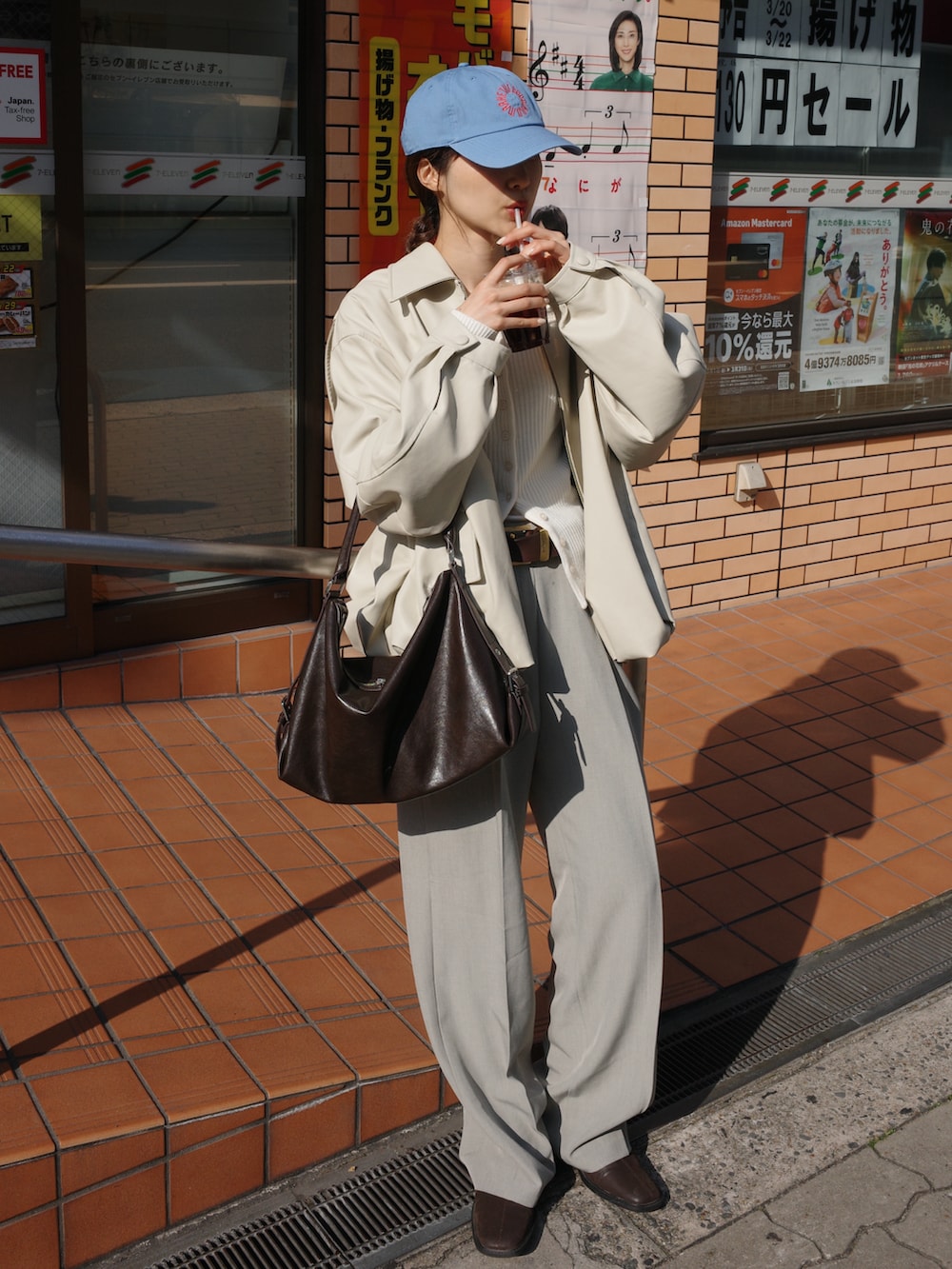 ブラウン系のショルダーバッグ、ホワイト系のブルゾン、ベージュ系のパンツを着用したレディースの春コーディネートの2枚目の写真