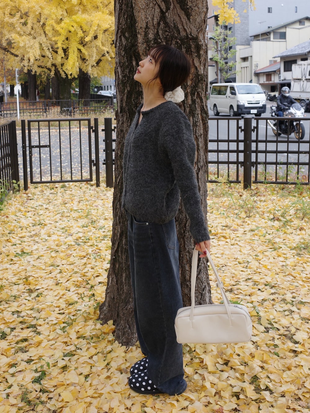 グレー系のニット/セーター、ブルー系のデニムパンツ、ホワイト系のショルダーバッグを着用したレディースの冬コーディネートの2枚目の写真
