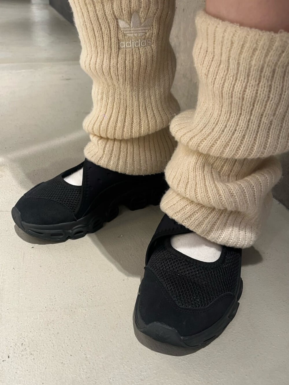 ブルー系のデニムパンツ、ブラック系のスニーカー、ホワイト系のレッグウォーマーを着用したレディースの夏コーディネートの4枚目の写真