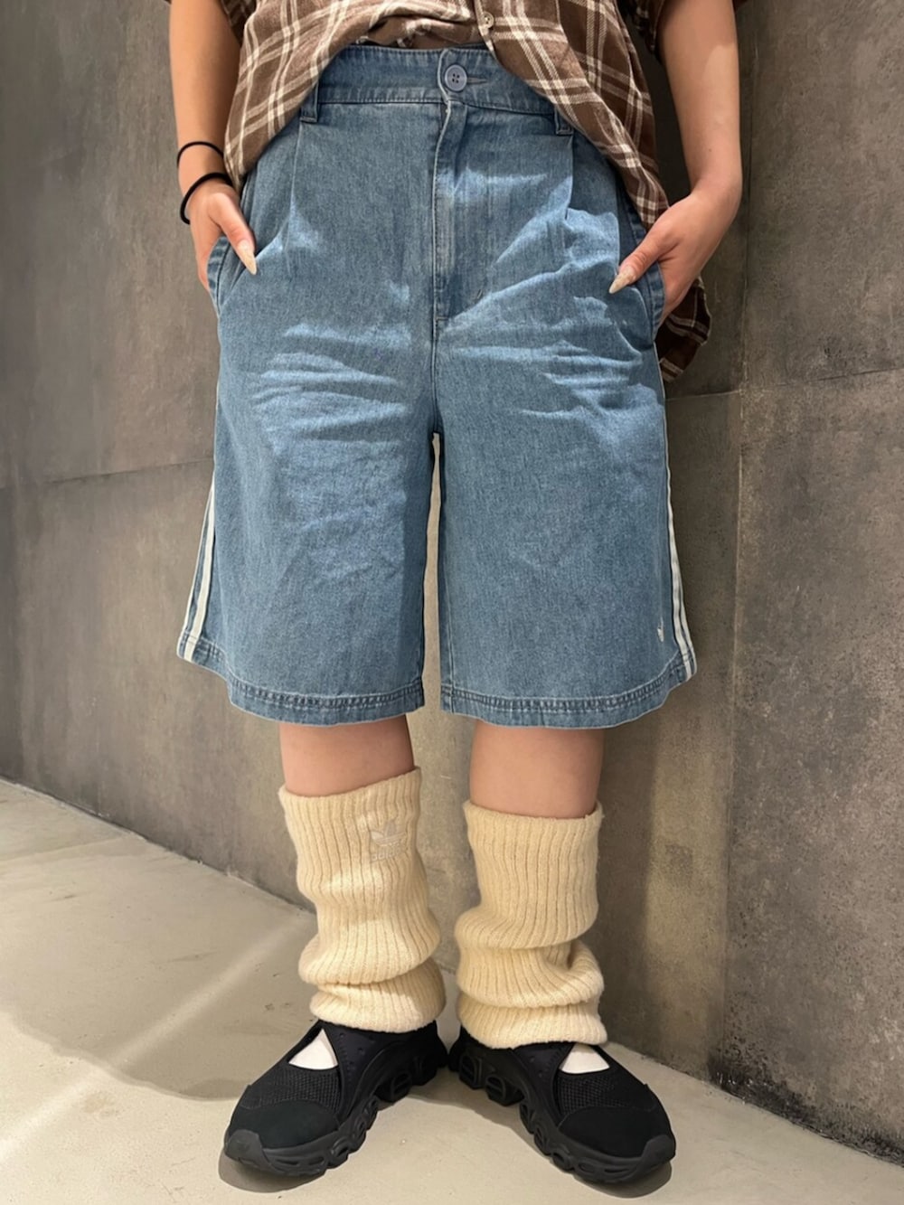 ブルー系のデニムパンツ、ブラック系のスニーカー、ホワイト系のレッグウォーマーを着用したレディースの夏コーディネートの3枚目の写真