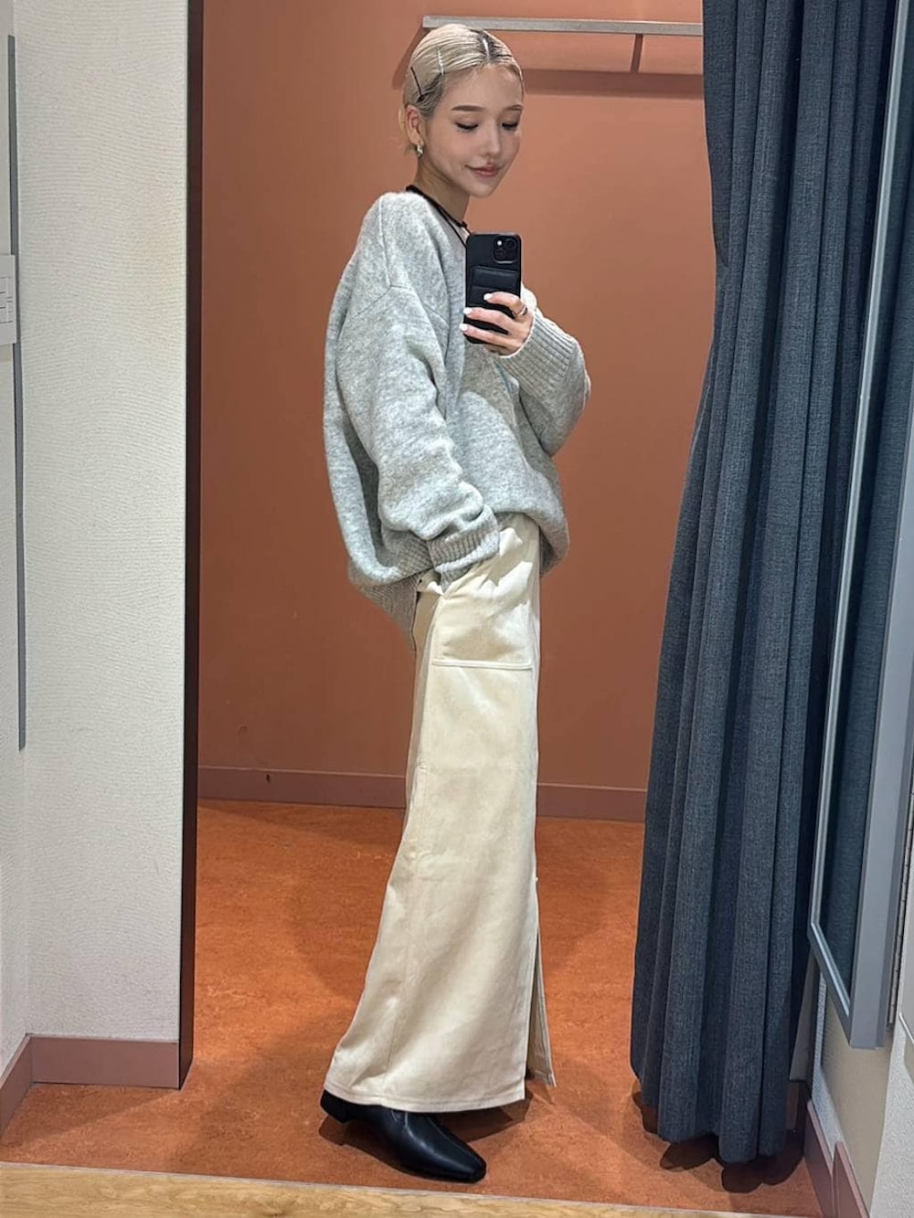 ホワイト系のスカート、ブラック系のブーツ、グレー系のニット/セーターを着用したレディースの冬コーディネートの3枚目の写真