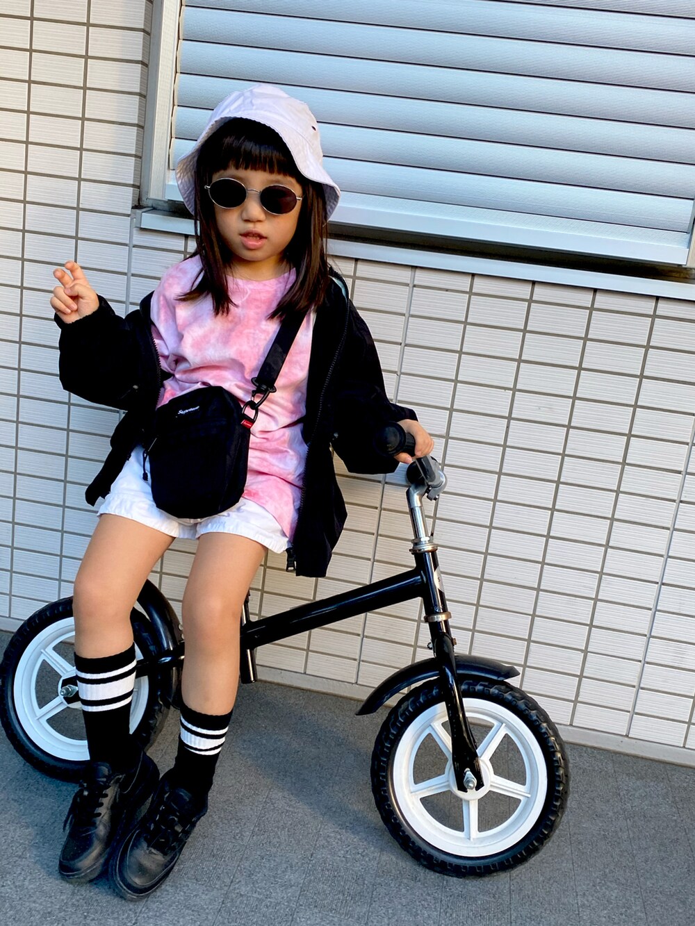 ブラック系のショルダーバッグ、ブラック系のスニーカー、ピンク系のTシャツ/カットソーを着用したキッズの冬コーディネートの2枚目の写真