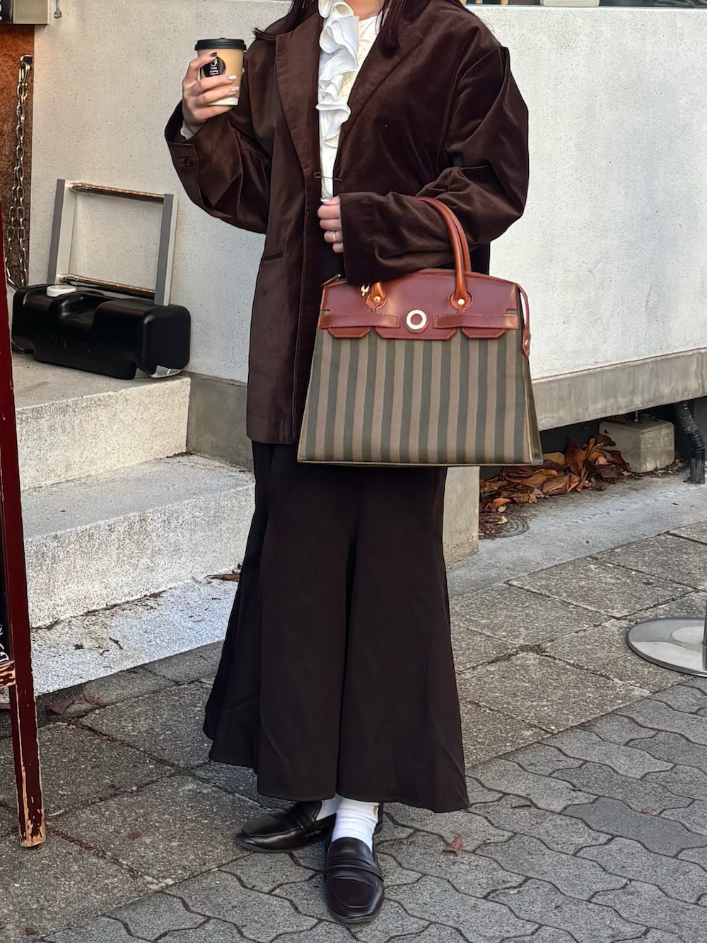 ブラウン系のテーラードジャケット、ブラウン系のスカート、ブラウン系のレインシューズを着用したレディースの冬コーディネートの2枚目の写真