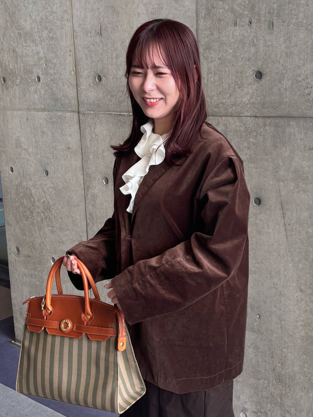 ブラウン系のテーラードジャケット、ブラウン系のスカート、ブラウン系のレインシューズを着用したレディースの冬コーディネートの3枚目の写真