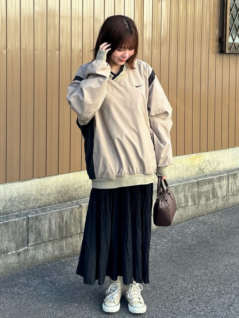 ブラウン系のボストンバッグ、ベージュ系のスニーカー、ベージュ系のナイロンジャケットを着用したレディースの春コーディネートの2枚目の写真