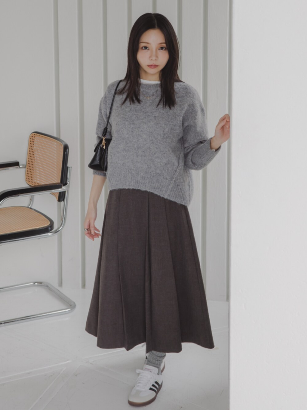 ホワイト系のTシャツ/カットソー、グレー系のスカート、グレー系のニット/セーターを着用したレディースの秋コーディネートの2枚目の写真