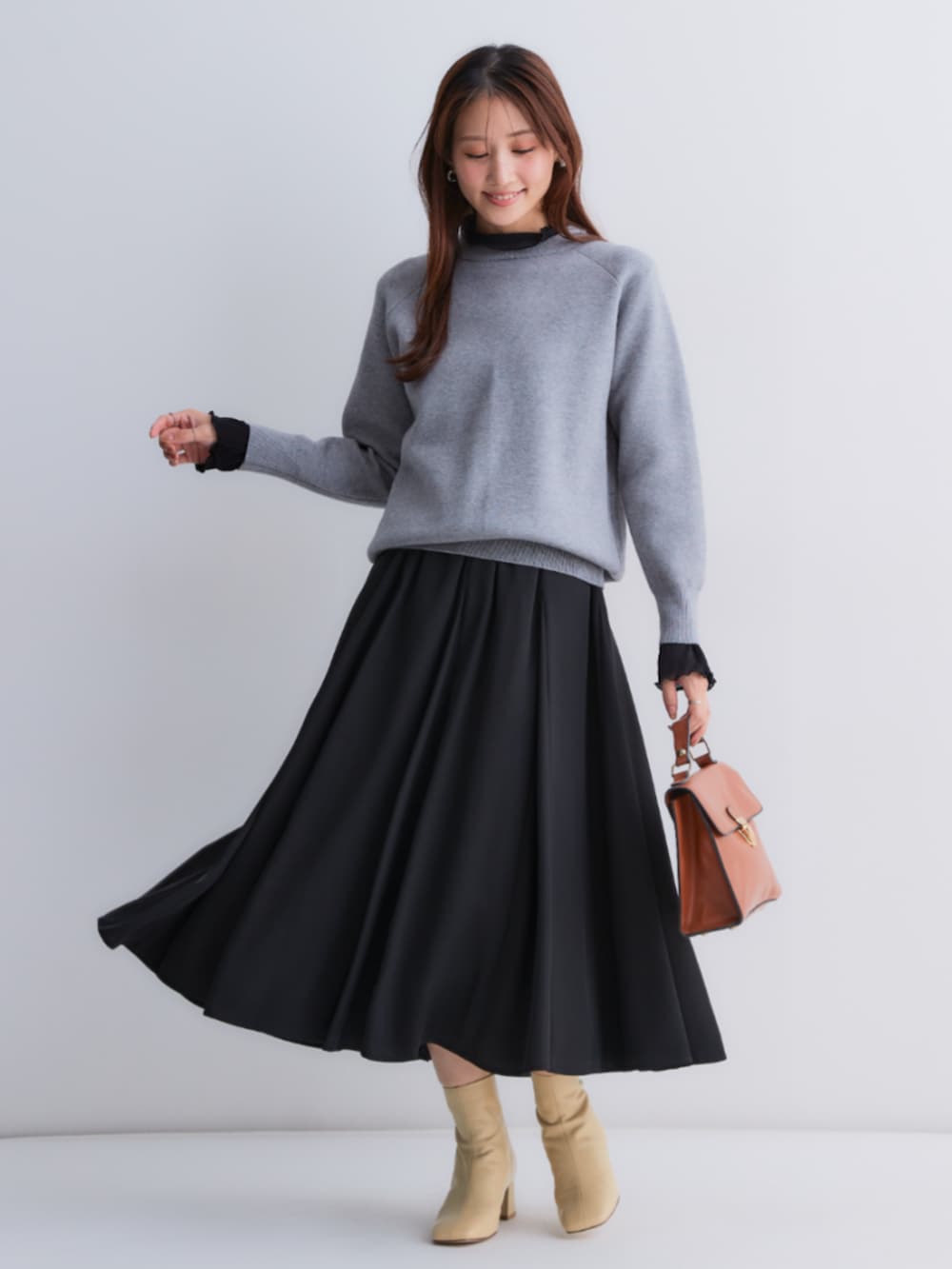 ブラック系のスカート、グレー系のニット/セーター、ブラック系のTシャツ/カットソーを着用したレディースの秋コーディネートの3枚目の写真