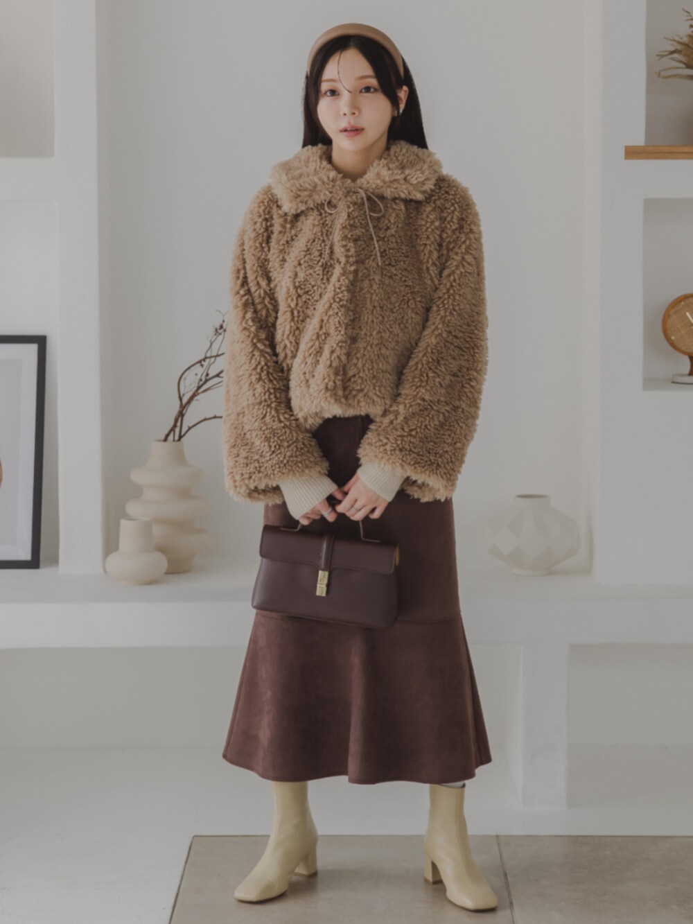 ブラウン系のスカート、ホワイト系のブーツ、ベージュ系のニット/セーターを着用したレディースの秋コーディネートの2枚目の写真