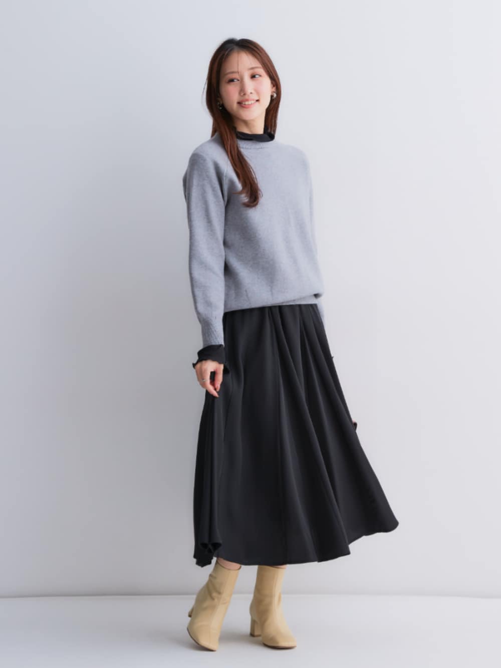 ブラック系のスカート、グレー系のニット/セーター、ブラック系のTシャツ/カットソーを着用したレディースの秋コーディネートの2枚目の写真