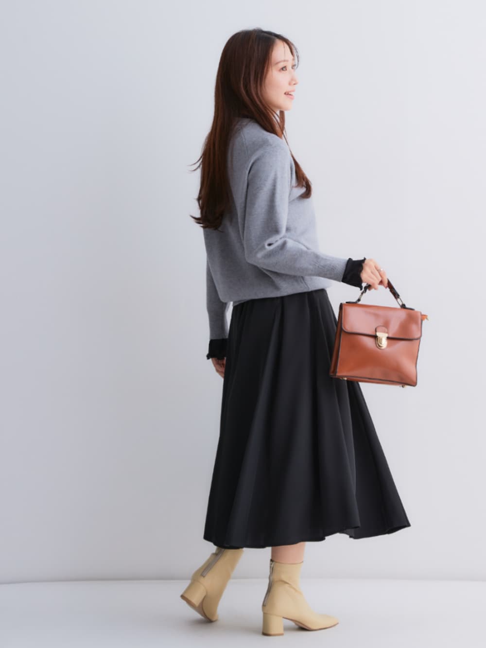 ブラック系のスカート、グレー系のニット/セーター、ブラック系のTシャツ/カットソーを着用したレディースの秋コーディネートの4枚目の写真