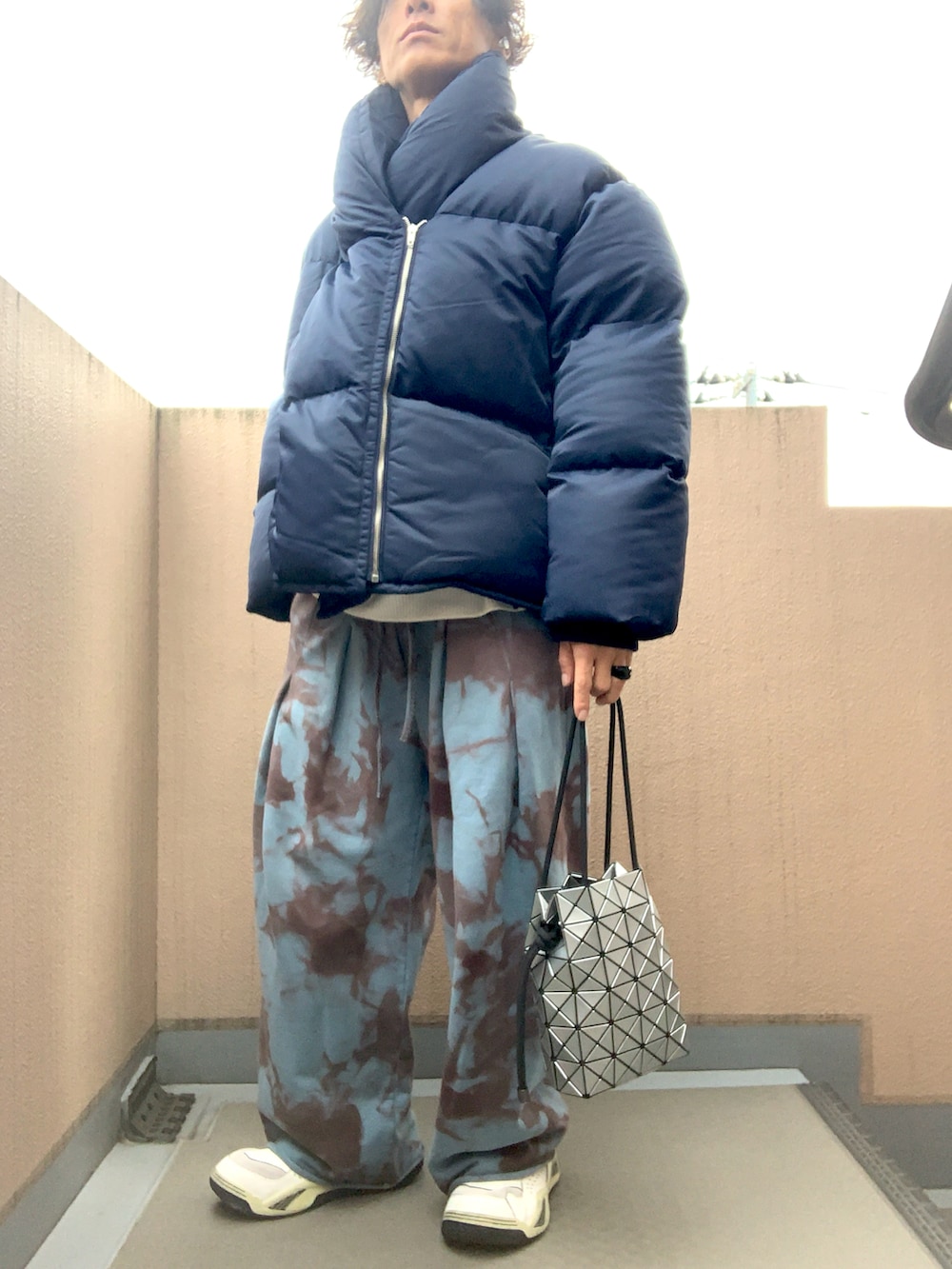 ブルー系のダウンジャケット/コート、ブルー系のスウェットパンツ、シルバー系のエコバッグ/サブバッグを着用したメンズの冬コーディネートの2枚目の写真