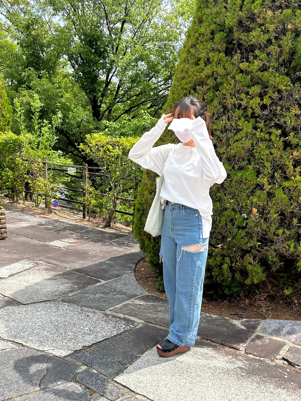 ブルー系のデニムパンツ、ホワイト系のTシャツ/カットソー、ホワイト系のトートバッグを着用したレディースの春コーディネートの4枚目の写真