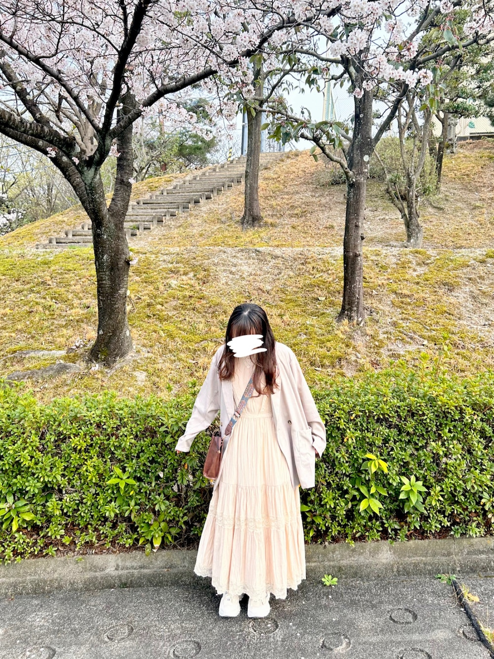 ベージュ系のテーラードジャケット、ホワイト系のワンピース、ブラウン系のショルダーバッグを着用したレディースの春コーディネートの2枚目の写真