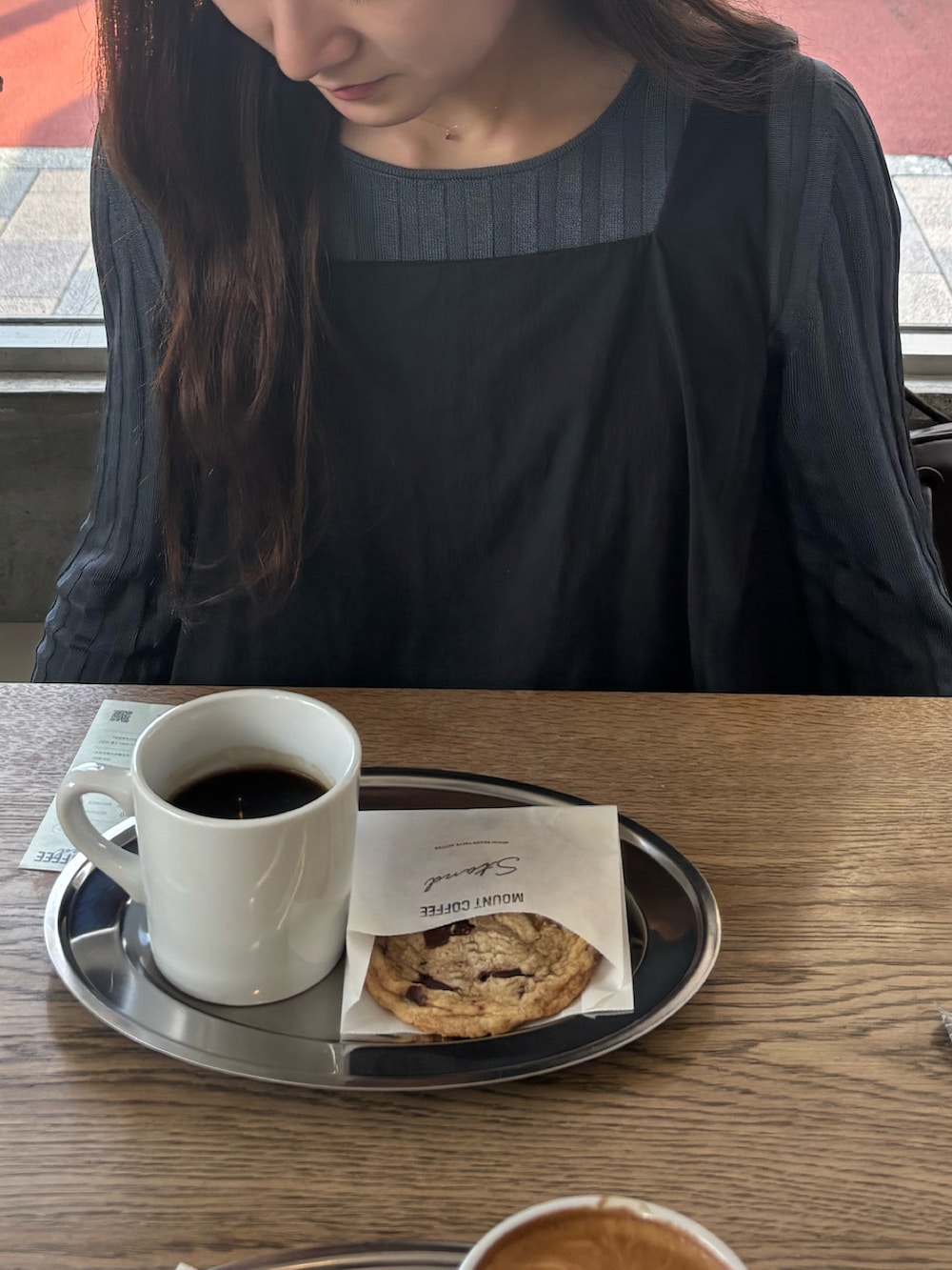 ブルー系のデニムパンツ、ブラック系のワンピース、ブルー系のニット/セーターを着用したレディースの秋コーディネートの2枚目の写真