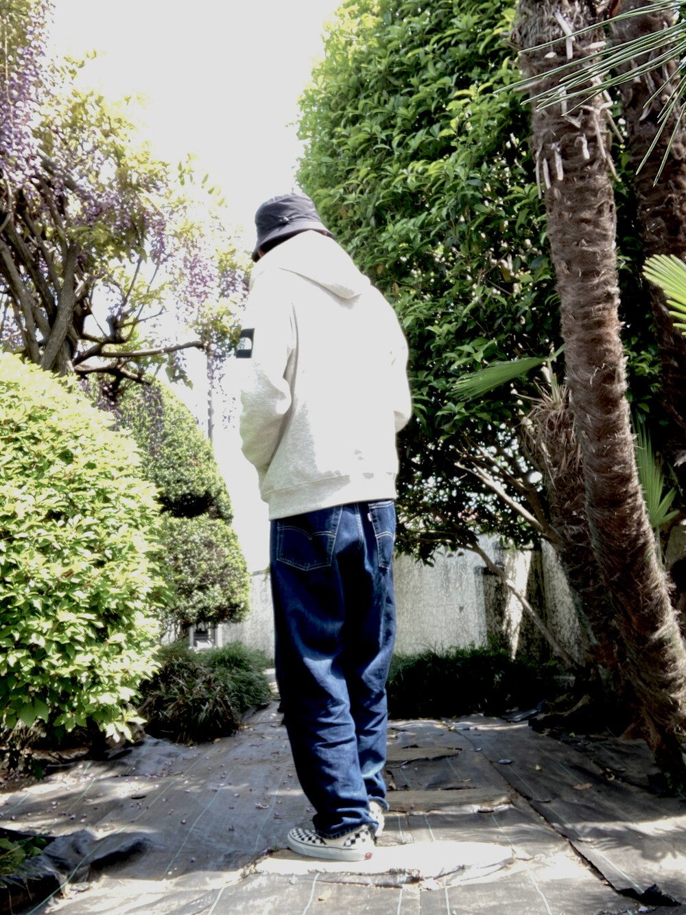 ベージュ系のパーカー、ブルー系のデニムパンツ、その他のスニーカーを着用したメンズの春コーディネートの3枚目の写真