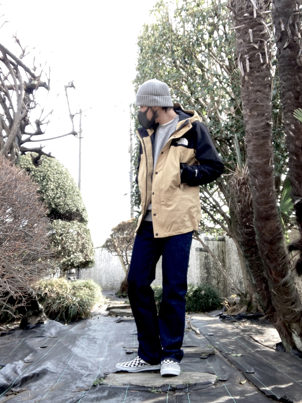 ベージュ系のマウンテンパーカー、グレー系のスウェット、ブルー系のデニムパンツを着用したメンズの春コーディネートの2枚目の写真