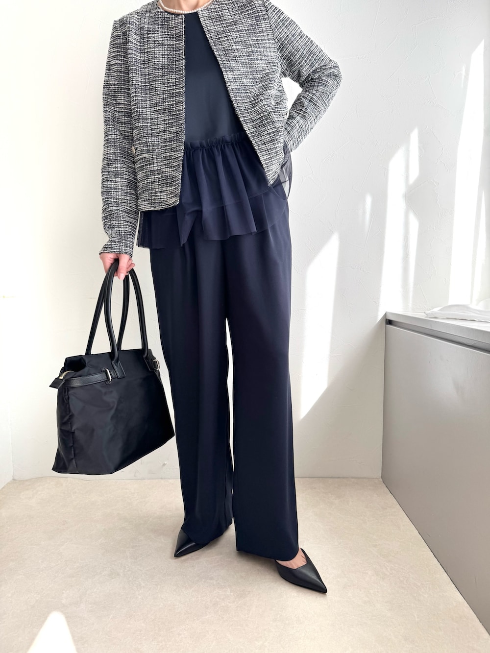 ブラック系のノーカラージャケット、ブルー系のシャツ/ブラウス、ブラック系のトートバッグを着用したレディースの春コーディネートの6枚目の写真