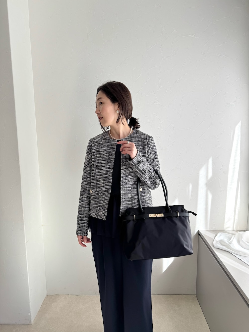 ブラック系のノーカラージャケット、ブルー系のシャツ/ブラウス、ブラック系のトートバッグを着用したレディースの春コーディネートの3枚目の写真