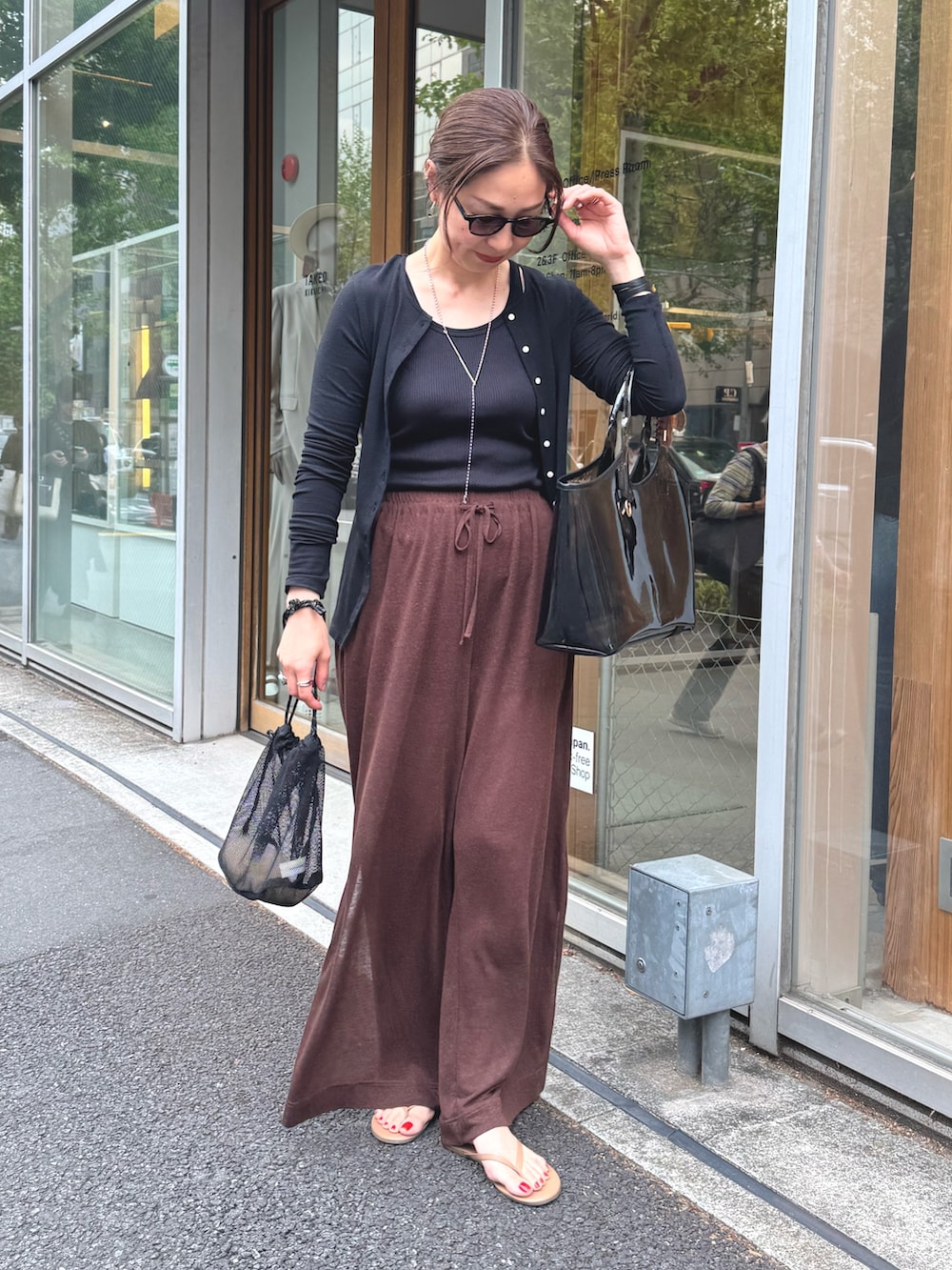 ブラウン系のその他パンツ、ブラック系のカーディガン/ボレロ、シルバー系のネックレスを着用したレディースの夏コーディネートの8枚目の写真