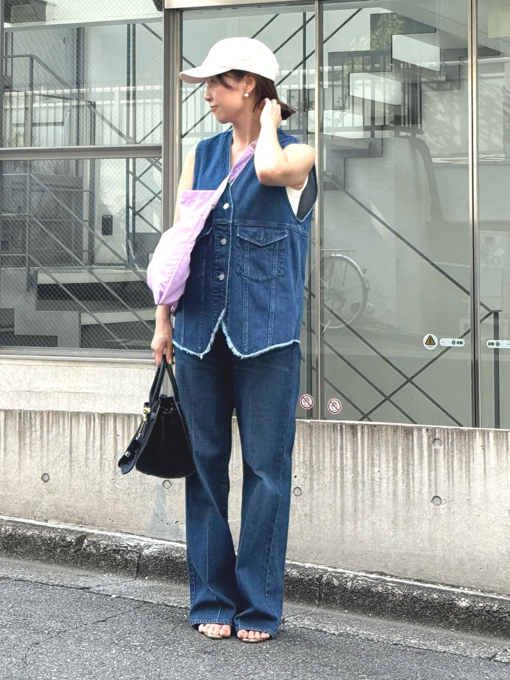 ブルー系のデニムパンツ、ブルー系のベスト、ブラック系のトートバッグを着用したレディースの夏コーディネートの2枚目の写真