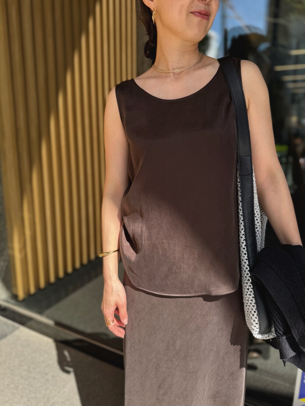 ブラウン系のスカート、ブラック系のベスト、グレー系のショルダーバッグを着用したレディースの夏コーディネートの8枚目の写真
