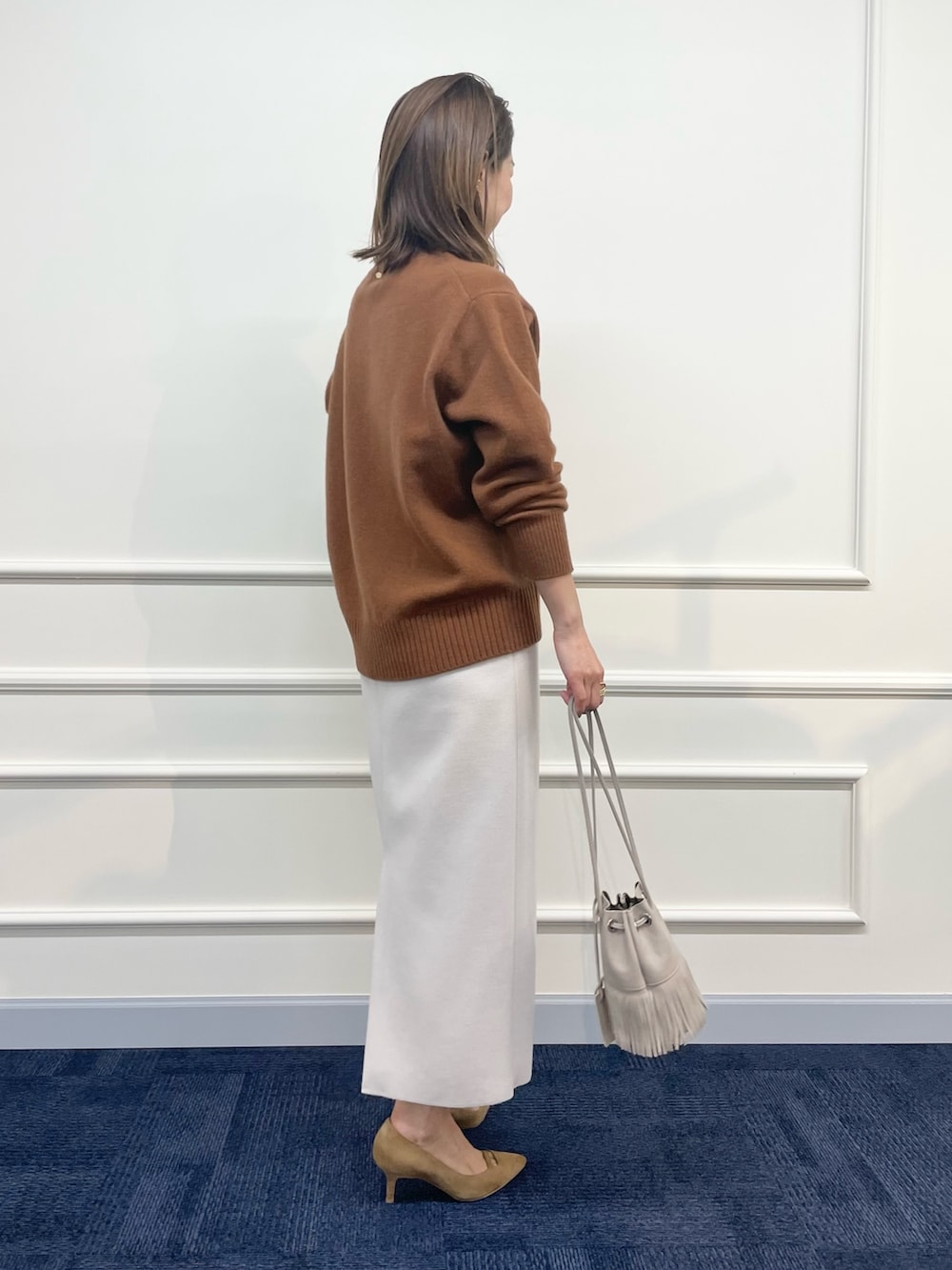 ベージュ系のダウンジャケット/コート、ブラウン系のニット/セーター、ベージュ系のスカートを着用したレディースの秋コーディネートの8枚目の写真