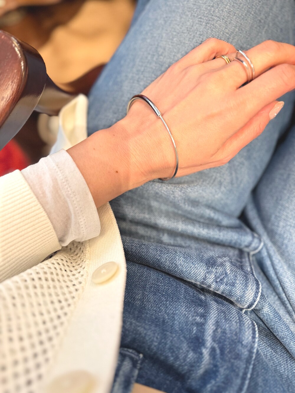 ブルー系のデニムパンツ、ブラウン系のショルダーバッグ、ホワイト系のカーディガン/ボレロを着用したレディースの春コーディネートの7枚目の写真